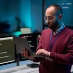 Bearded Man Holding Laptop in Cybersecurity Office