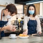 Asian Barista couple enjoy doing digital marketing in cafe restaurant.