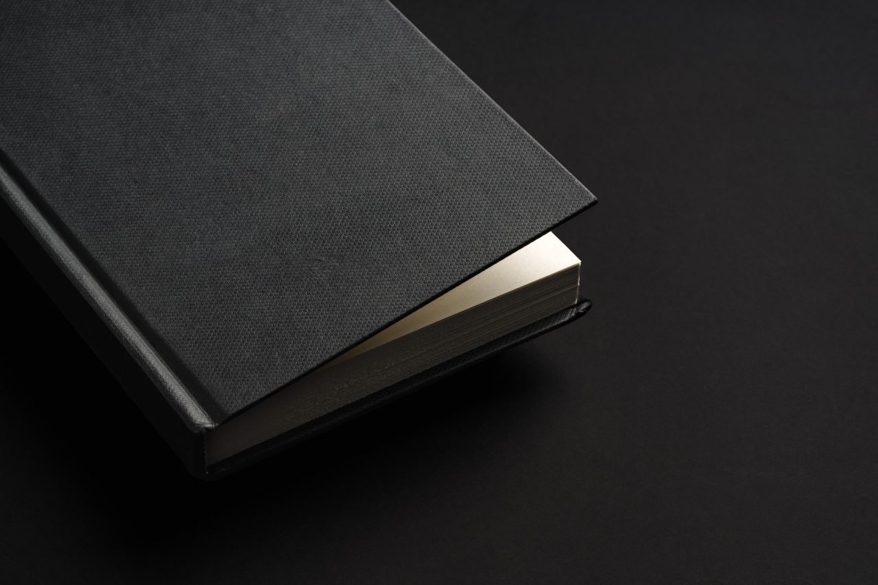 Black hardcover book or notepad mock up on black background