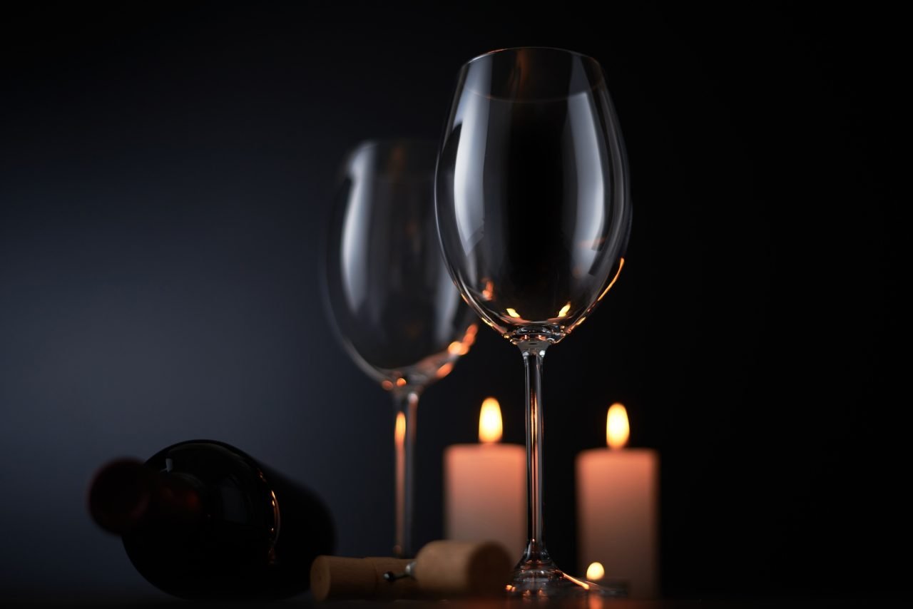 Elegant red wine glass and a wine bottle in black background
